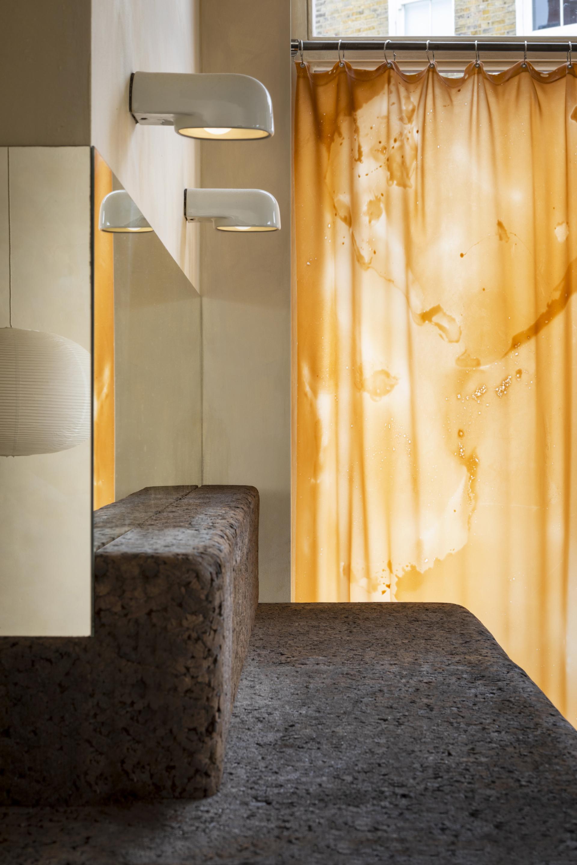 Design featuring salvaged cork seating, warm ambient lighting, and a vibrant bio-material curtain in sustainable store.