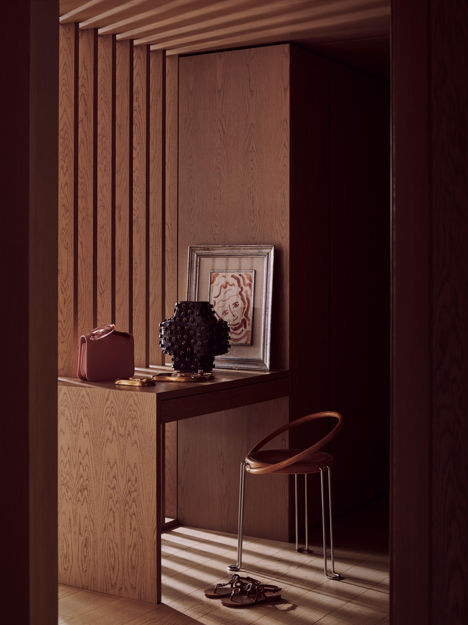 Stylish interior detail featuring a wooden desk, art piece, designer handbag, and modern chair in Roksanda's penthouse.
