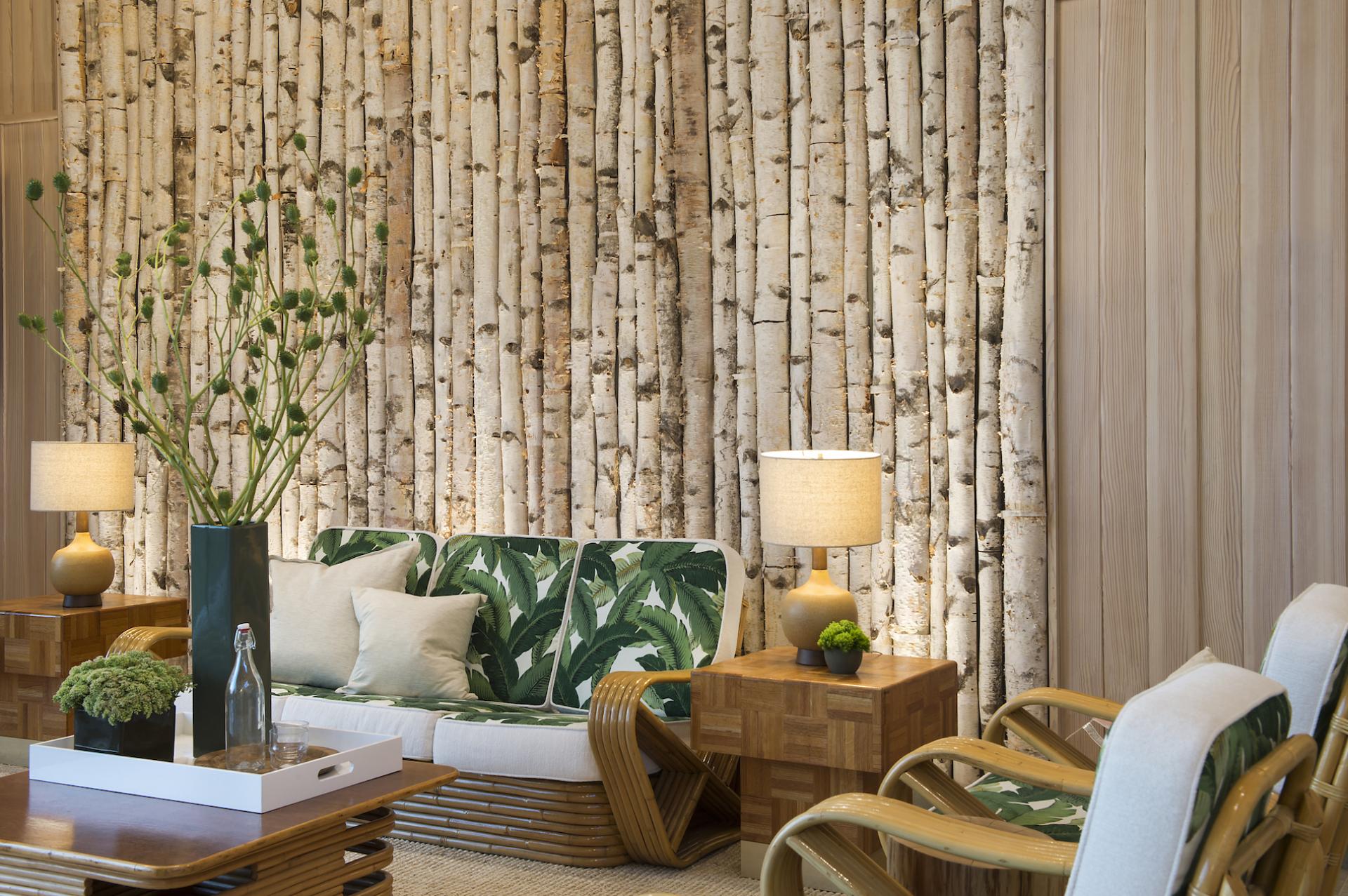 Stylish interior of Lazy Bear Pool House featuring a birch wall, tropical furniture, and cozy lighting.