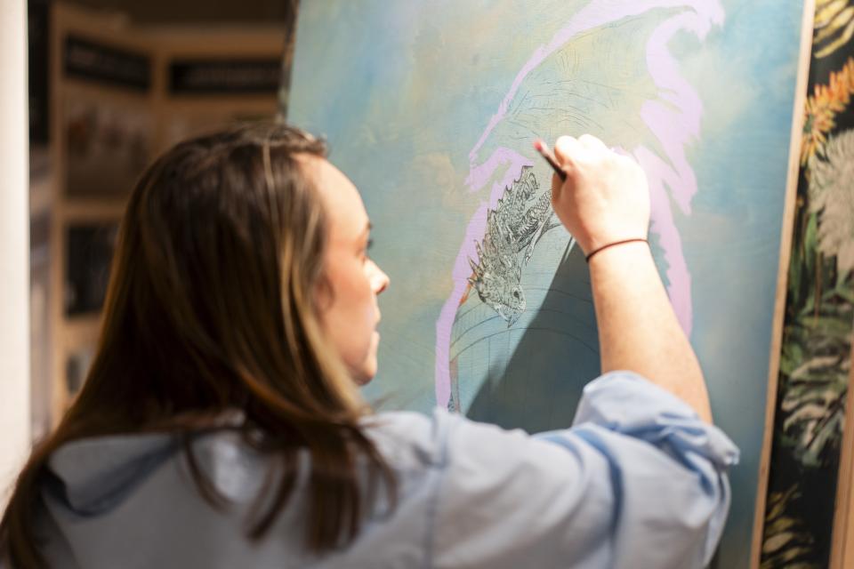 Artist painting a colorful mural, featuring a dragon, during the Material Source Studio celebration in Manchester.