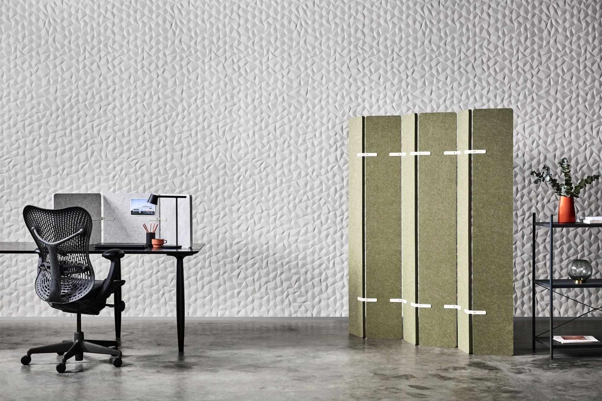 Tactile acoustic wall panels ION in a contemporary workspace featuring textured gray background, a desk, and decorative elements.