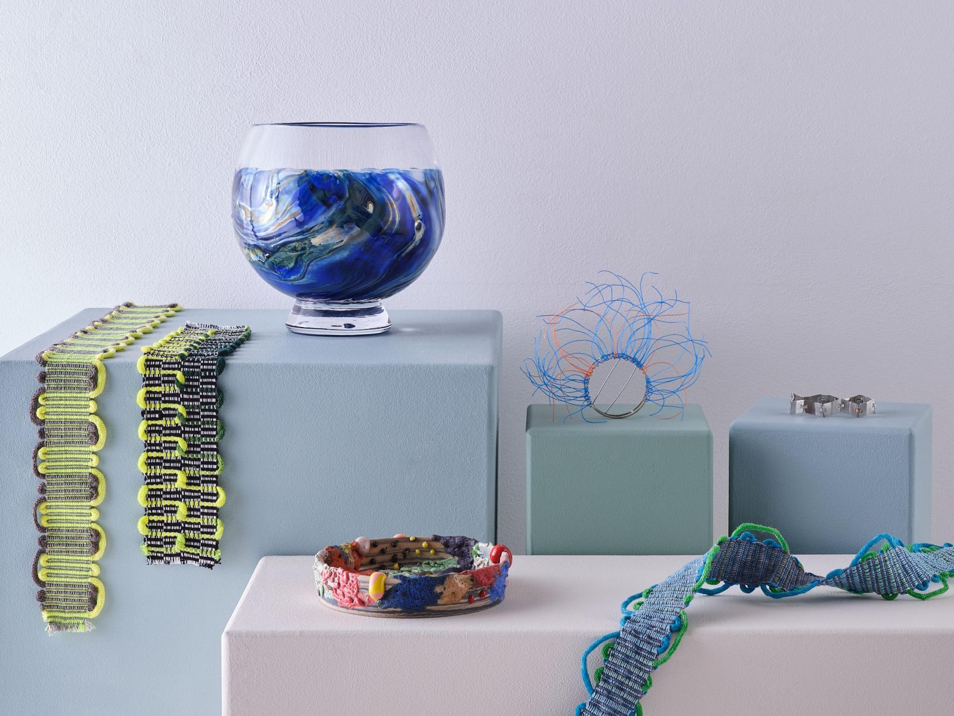 Elegant handmade glassware and unique jewelry pieces showcased on pastel pedestals, emphasizing sustainable design and craftsmanship.