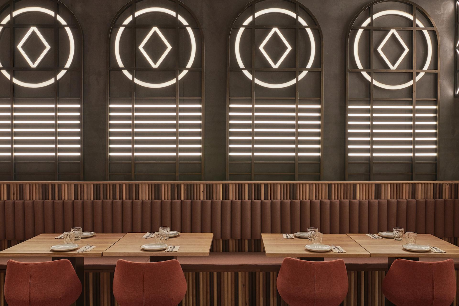 Modern restaurant interior design featuring illuminated geometric patterns, cozy seating, and elegantly set tables for diners.