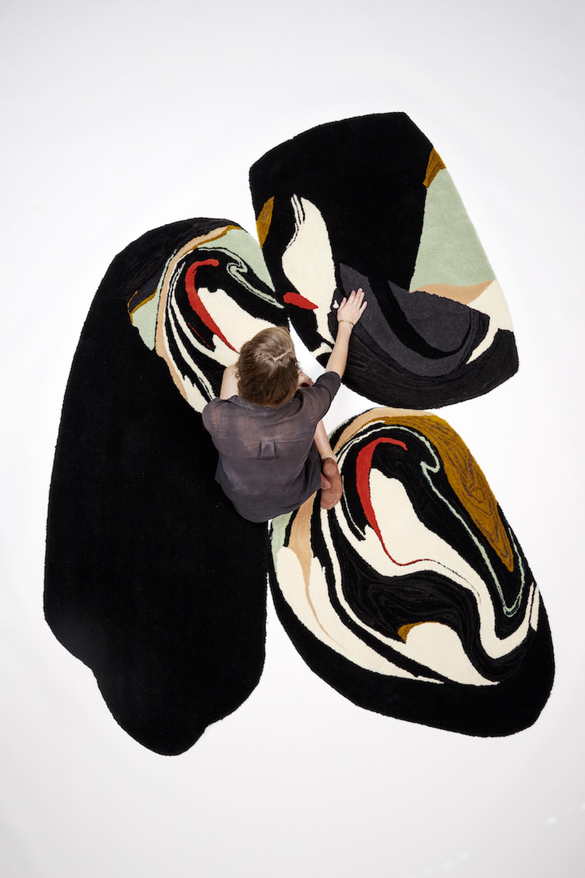 Contemporary German designer examines abstract, colorful rugs, showcasing innovative textile artistry and unique design identities.
