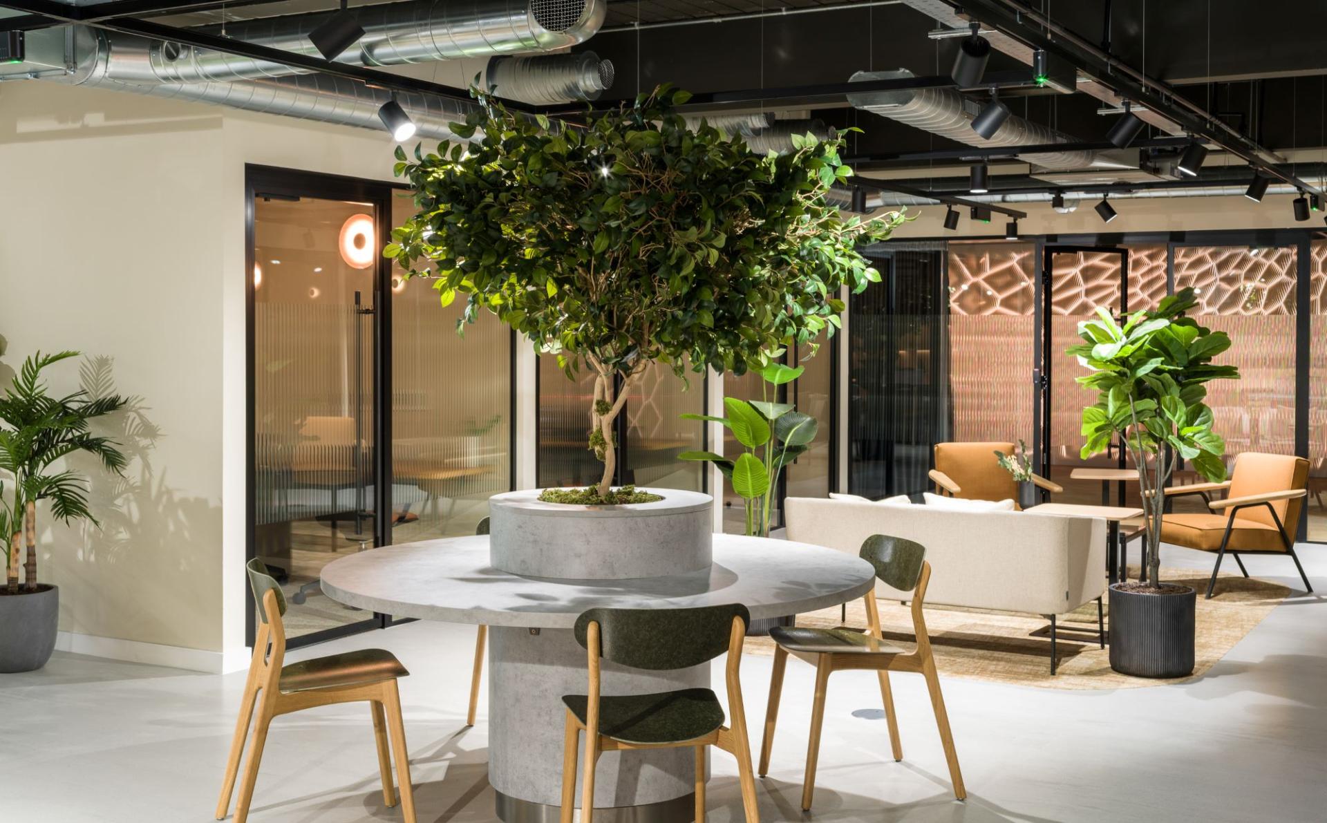 Stylish interior of a revitalized space featuring a round table, greenery, and modern seating at Alderley Park.