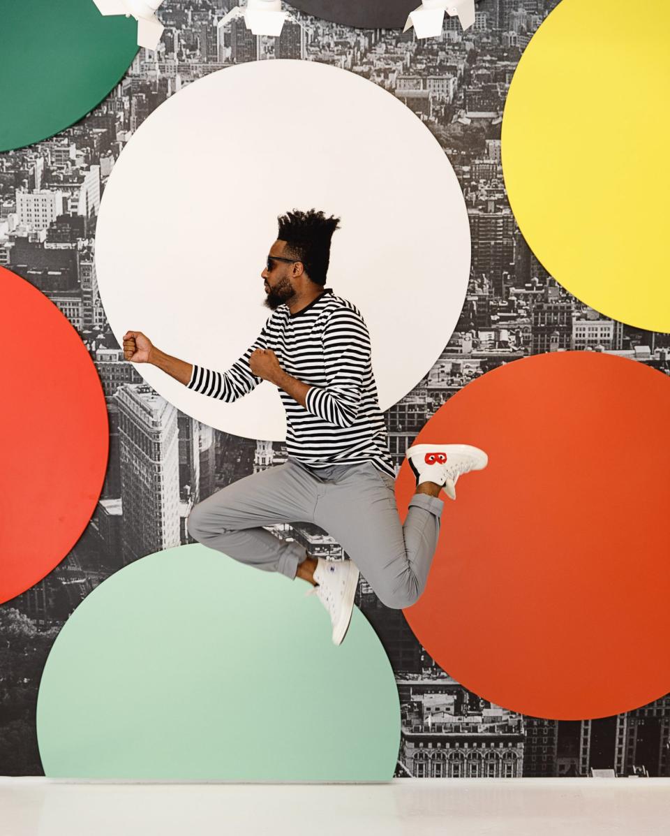 A person jumps joyfully in front of colorful circular backdrops at the vibrant Color Factory exhibition in New York City.