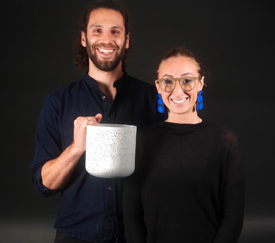 Elizabeth Bridges and Garrett Benisch showcase sustainable biomaterials with a speckled container, highlighting eco-friendly innovations.
