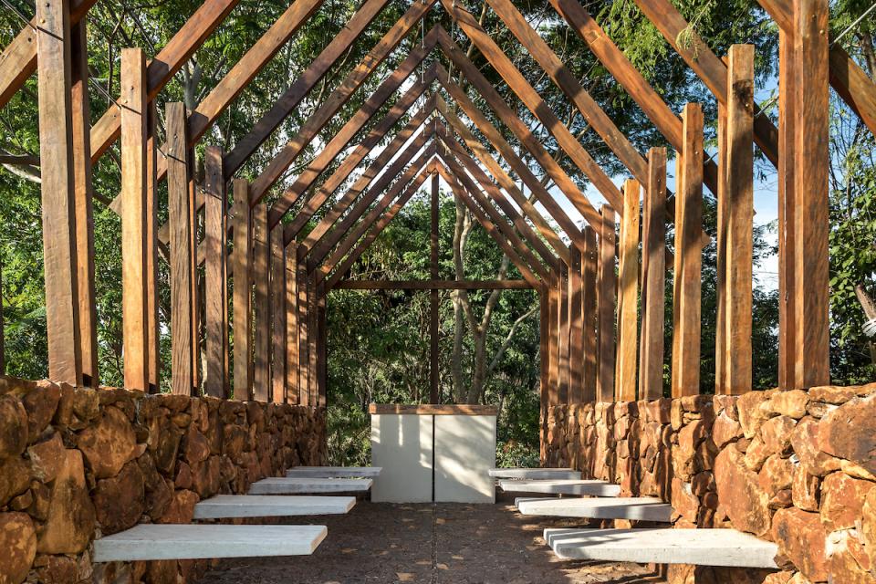 Rustic wooden structure with stone walls and benches, blending seamlessly with the lush natural surroundings of The Lake House in Brazil.