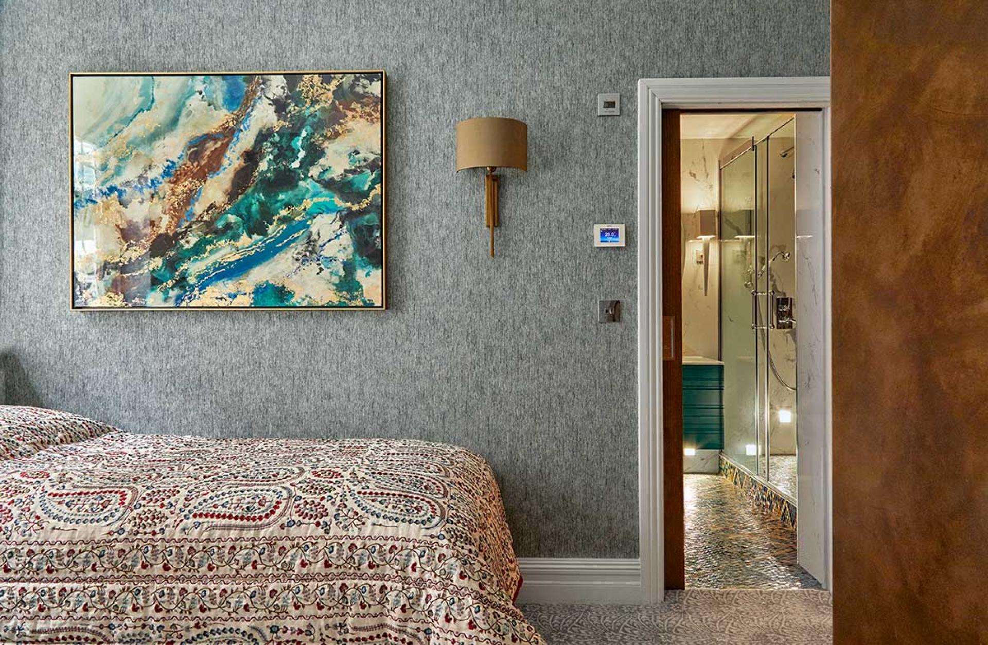 Modern Knightsbridge apartment featuring a stylish bedroom with vibrant artwork, luxurious bedding, and a bathroom entrance.