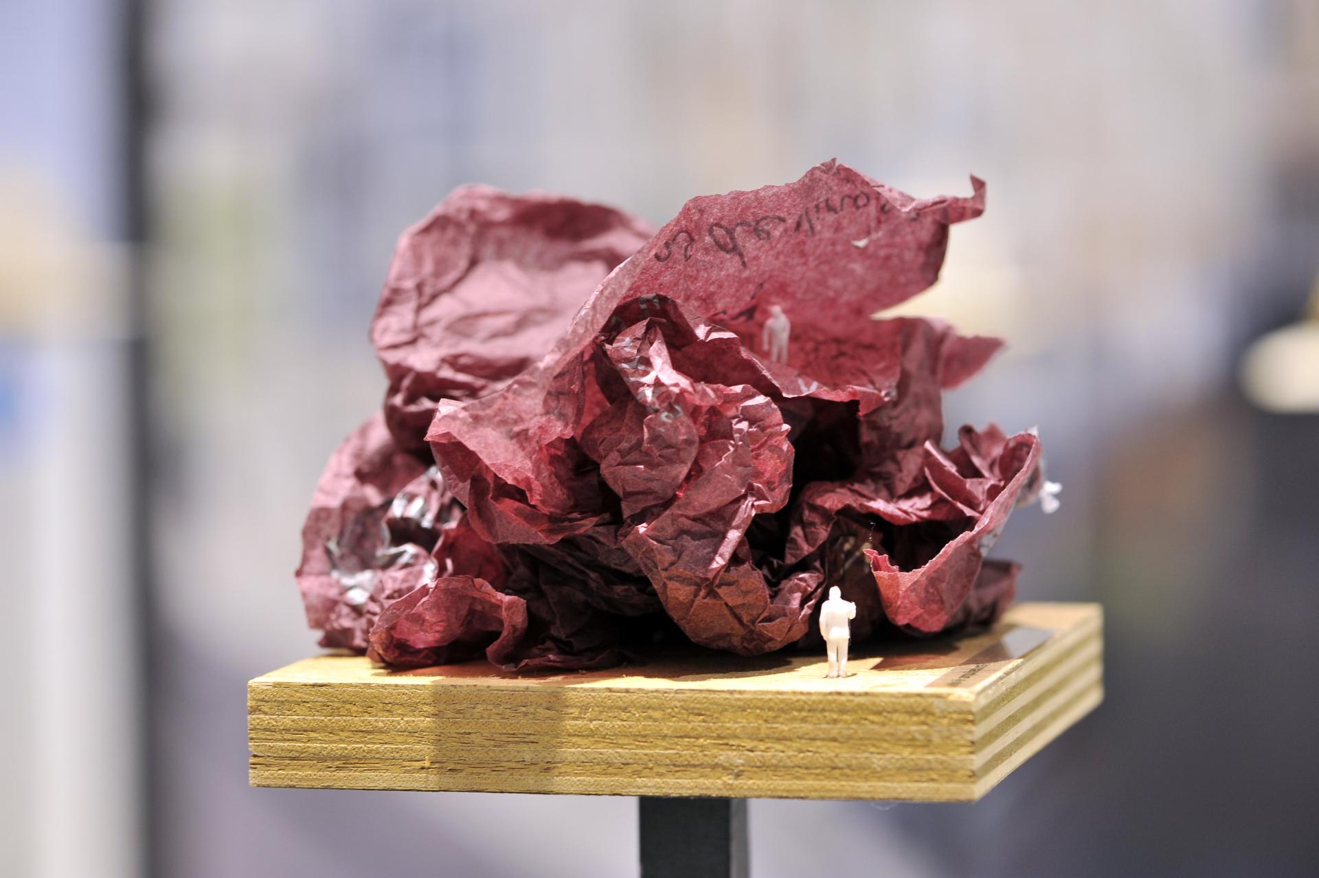 Architectural model by Sou Fujimoto with crumpled red paper and miniature figure, showcased at Japan House London.