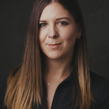 Sarah de Freitas, creative director at AXI Studio, with long brown hair against a dark background, embodying modern architecture and design.