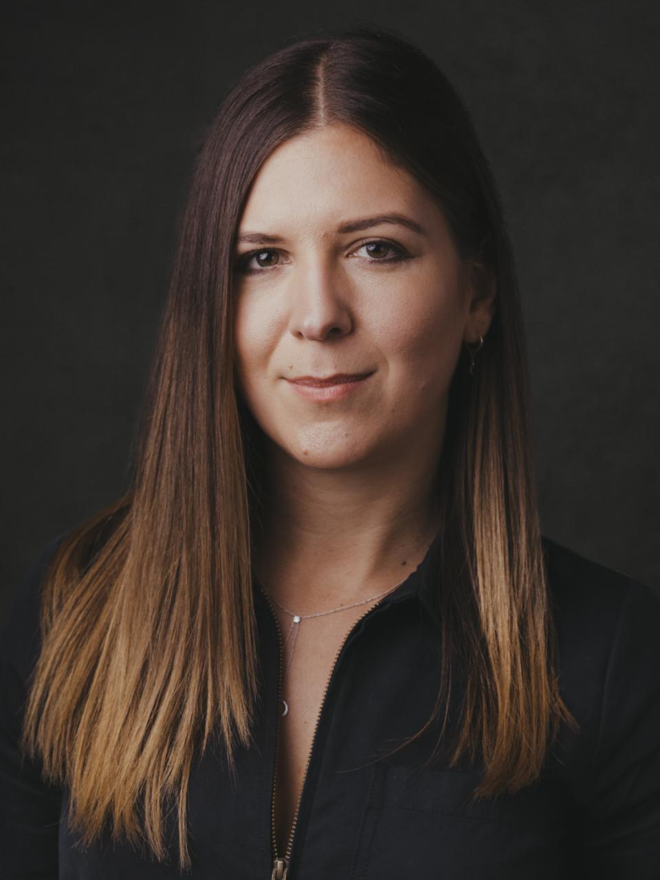 Sarah de Freitas, creative director at AXI Studio, with long brown hair against a dark background, embodying modern architecture and design.