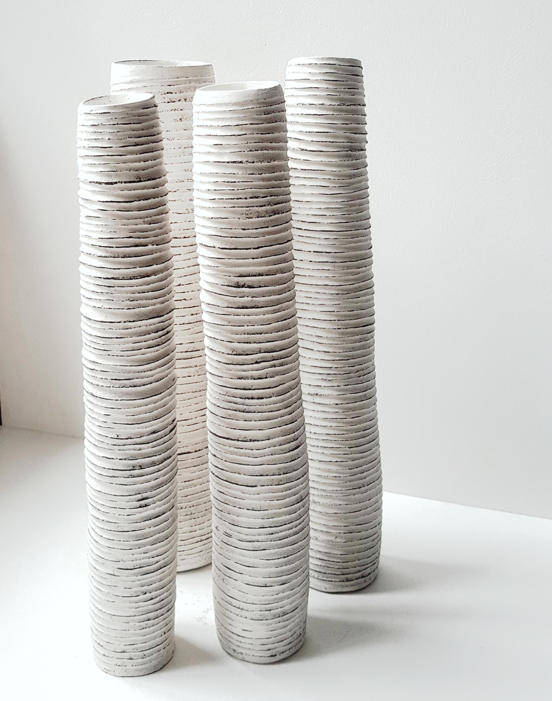 Textured white ceramic vases with a minimalist design, showcasing Michele Bianco's unique craftsmanship inspired by the outdoors.