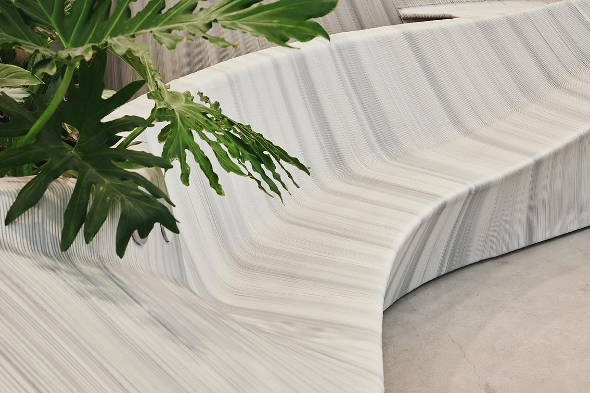 Sculpted multifunctional entrance furniture by The New Raw, featuring smooth curves and integrated greenery for modern design.
