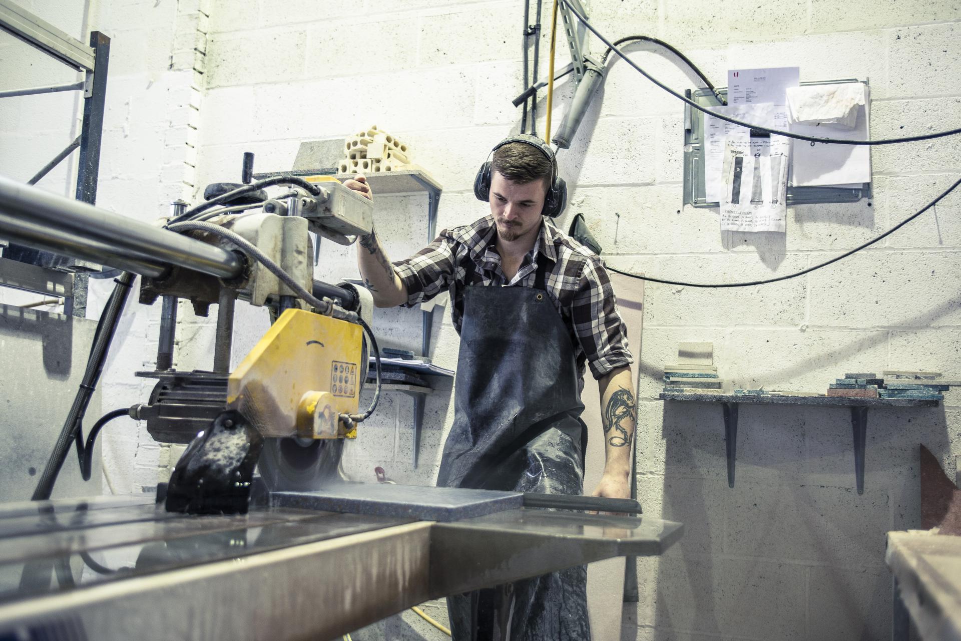 Craftsman working in a workshop, using a cutting machine to shape sustainable materials for innovative surface designs.