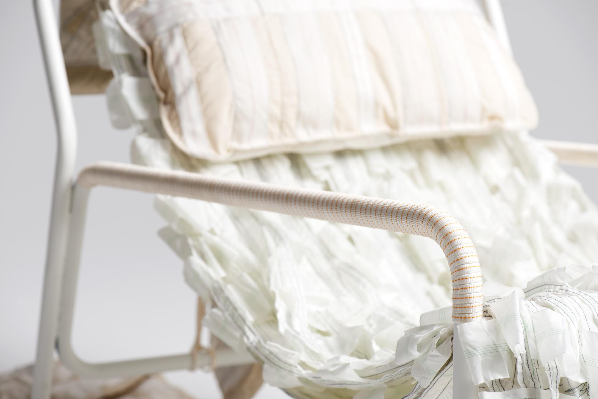 Innovative chair design featuring recycled parachute material and a sleek welded steel frame with decorative pillows.