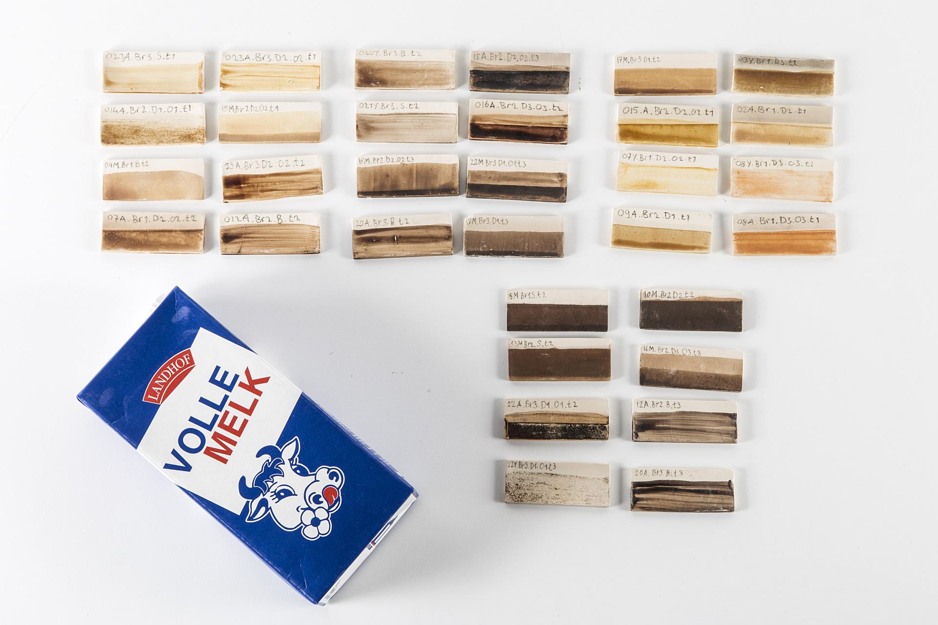 Samples of innovative biomaterials arranged on a table, alongside a carton labeled 'Volle Melk,' showcasing diverse colors and textures.