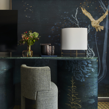 Elegant hotel room desk featuring a lamp, floral arrangement, and artistic wall design by Yabu Pushelberg at Park Lane New York.