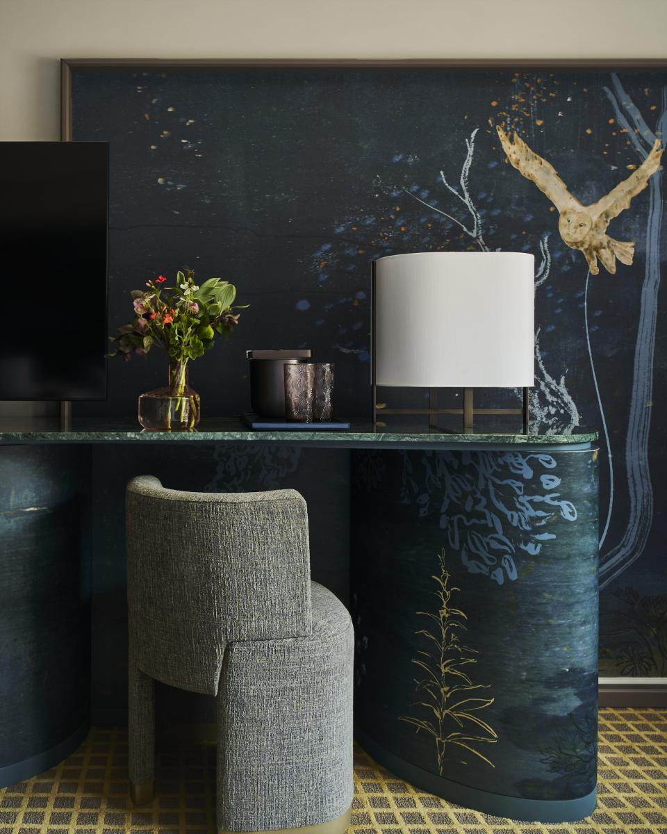 Elegant hotel room desk featuring a lamp, floral arrangement, and artistic wall design by Yabu Pushelberg at Park Lane New York.