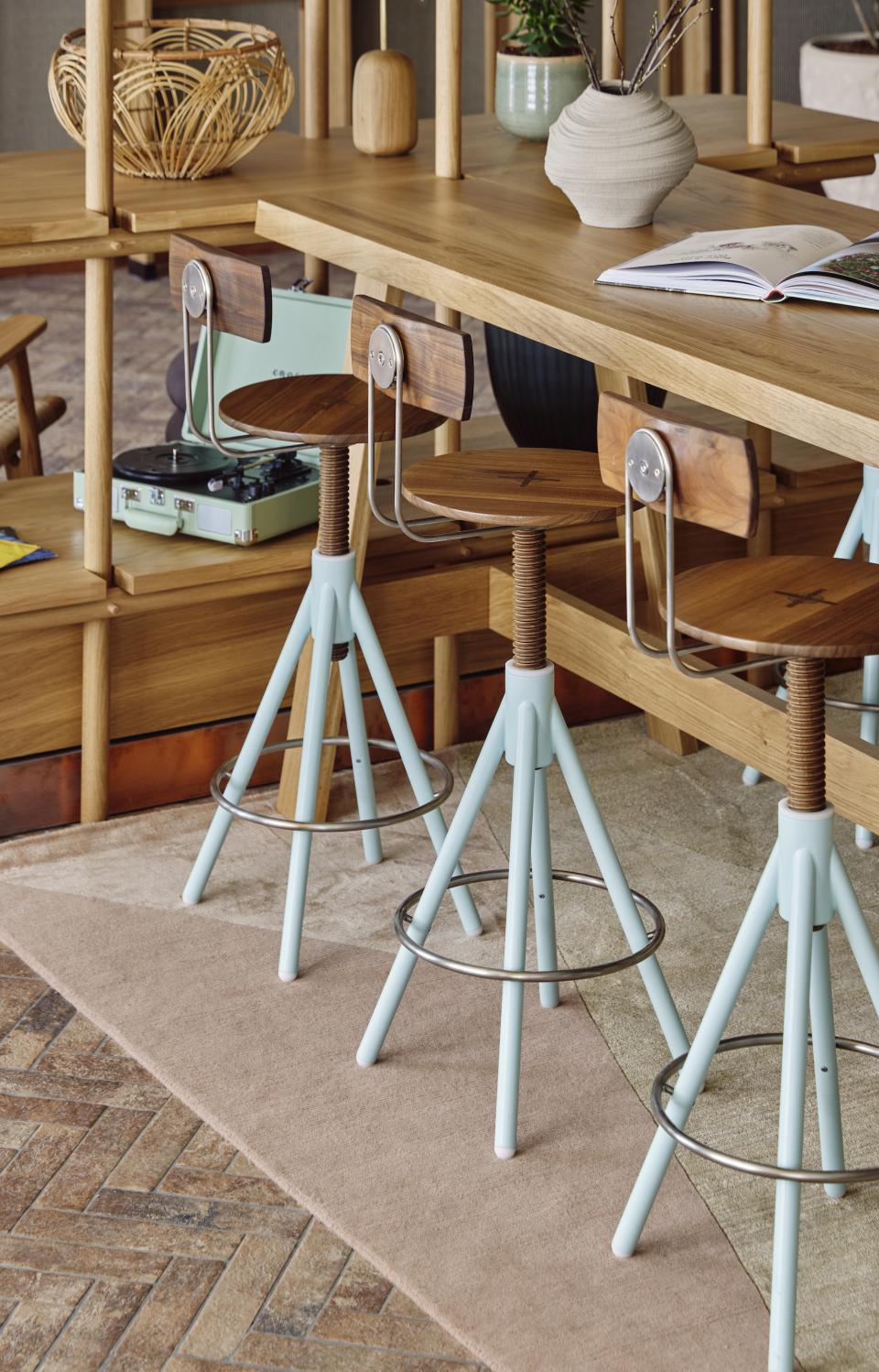 Modern bar stools and wooden table in the stylish interior of WunderLocke, a lifestyle aparthotel in Munich.