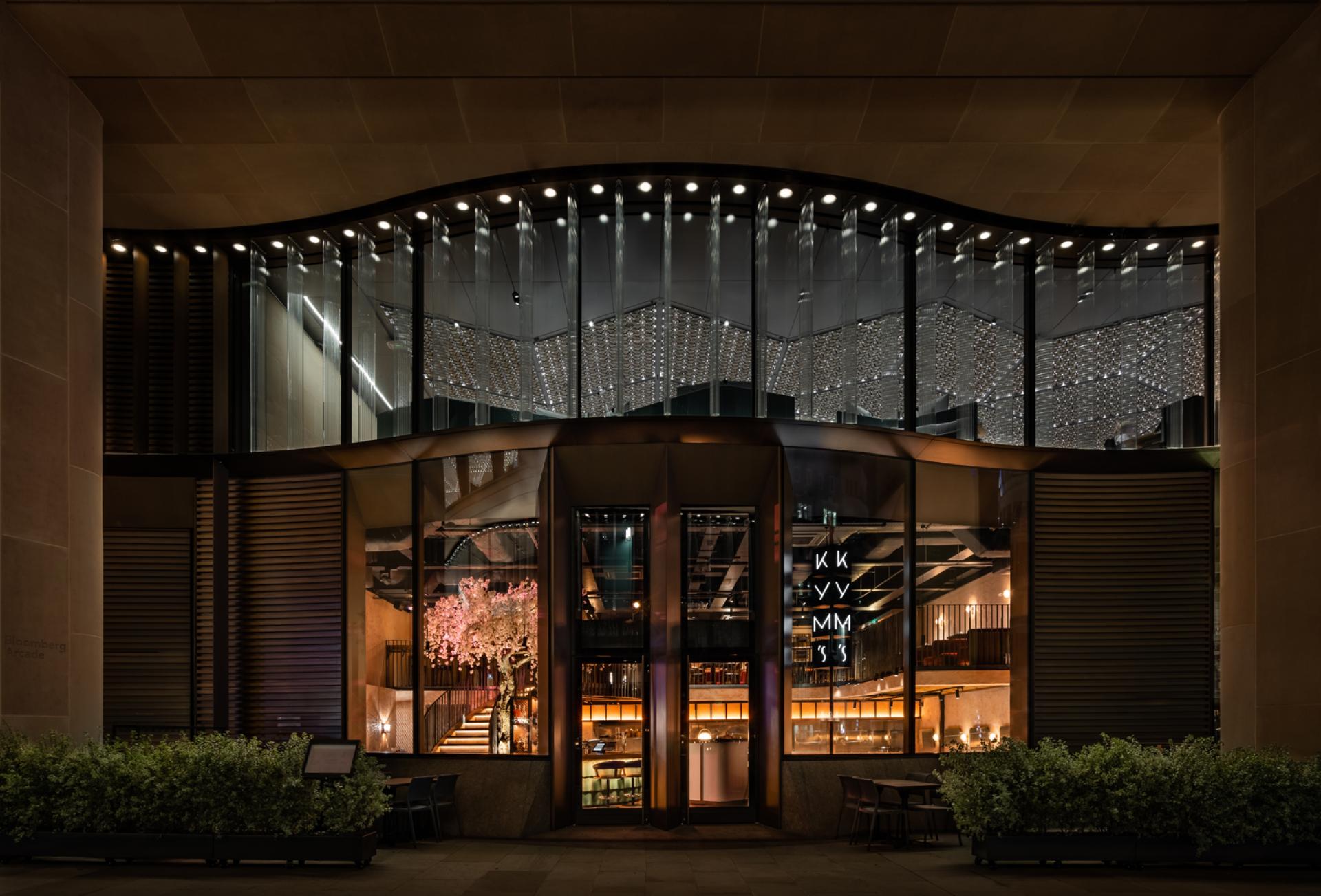 Modern architecture of Chef Andrew Wong's new restaurant at Bloomberg Arcade, featuring a striking glass facade and illuminated cherry tree.