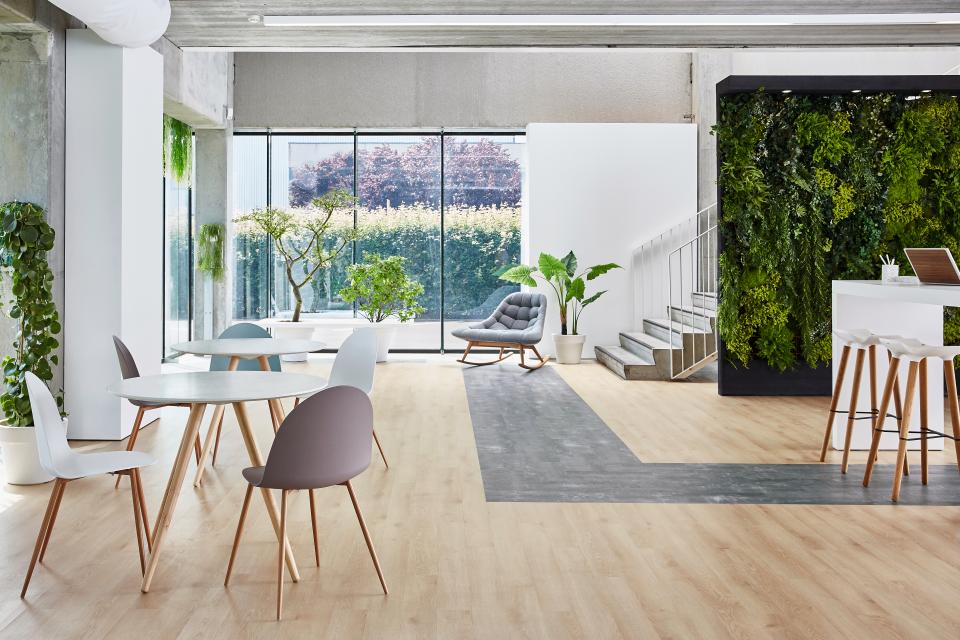 Sleek interior featuring Tarkett's sustainable flooring, modern furniture, and lush greenery in a bright, open space.
