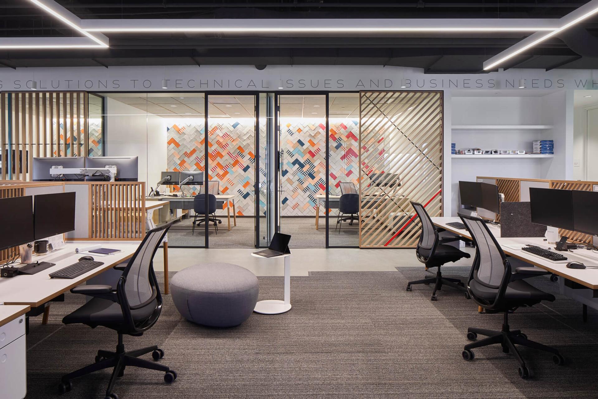 Modern office space showcasing collaborative design elements, featuring colorful wall art and stylish workstations by Dear Human.
