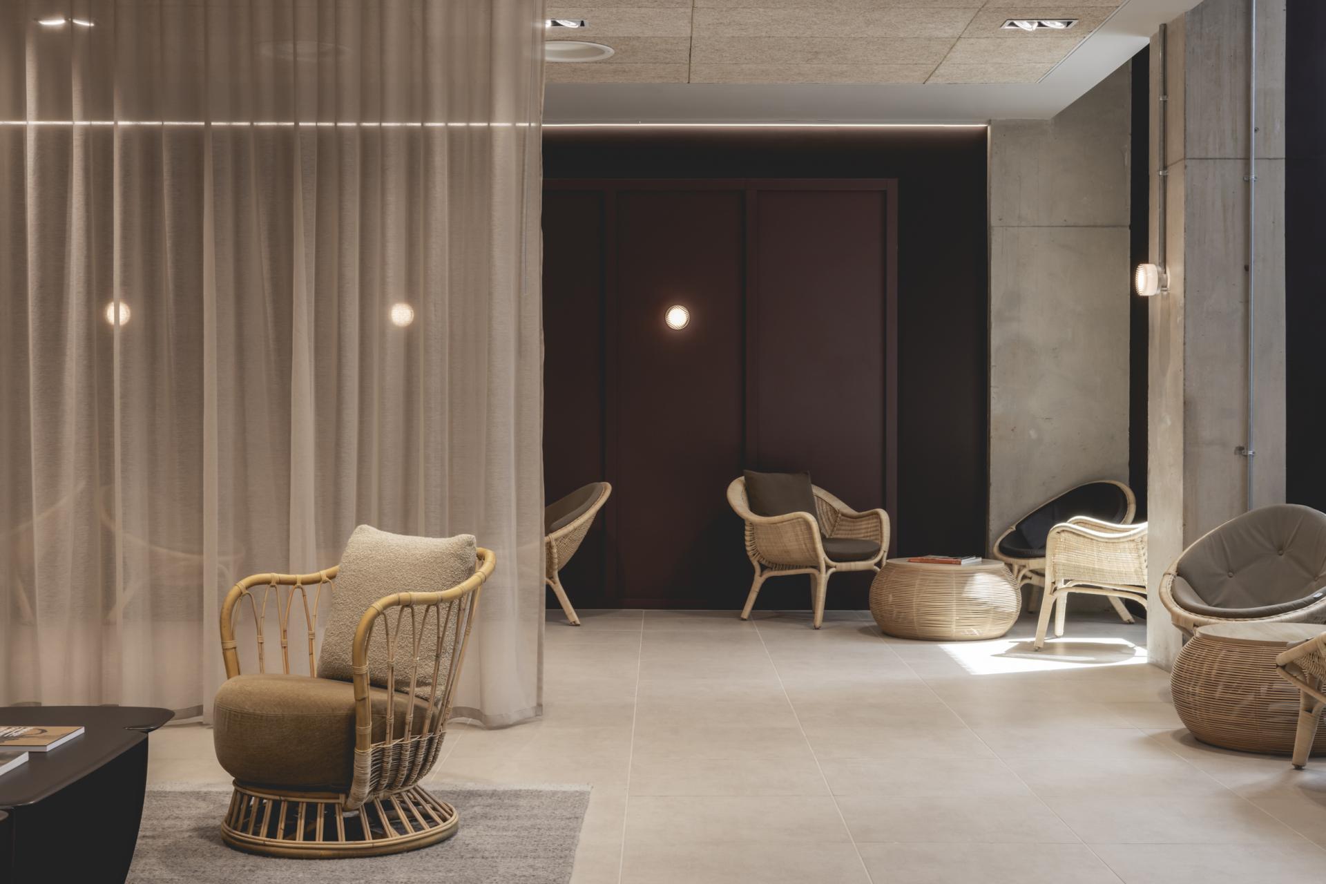 Contemporary interior design featuring a cozy seating area with rattan chairs, textures, and natural lighting elements.