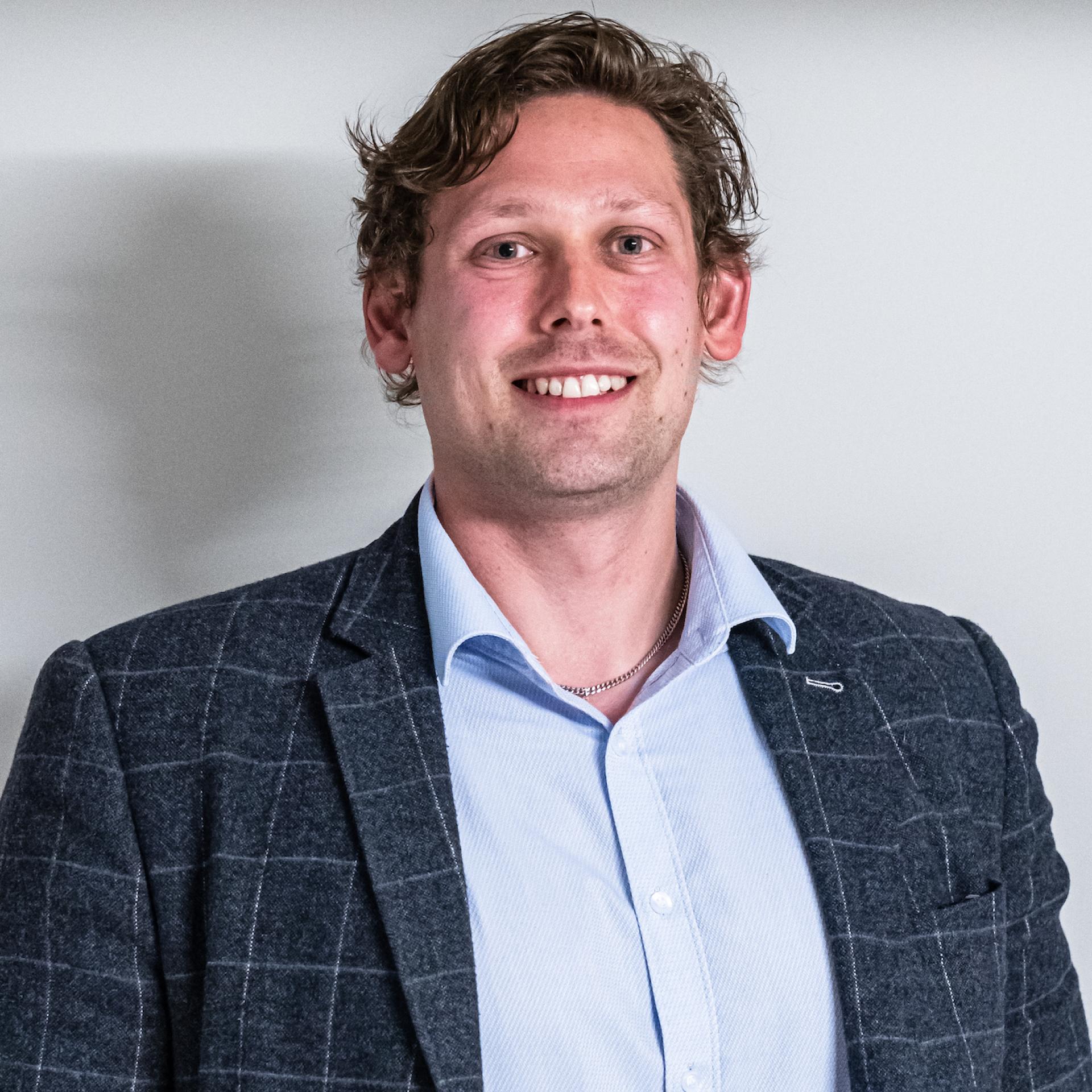 Professional man smiling in a blazer, representing the emerging trends in Manchester's property sector and co-living spaces.