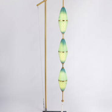 Sculptural lamp design featuring layered green and blue glass, highlighting modern waste materials and local craft heritage.