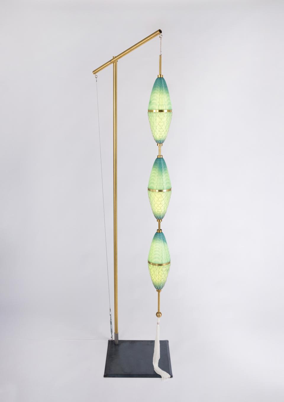 Sculptural lamp design featuring layered green and blue glass, highlighting modern waste materials and local craft heritage.