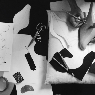 Creative workspace featuring hands designing and cutting various textile patterns and shapes for the May Wild Studio exhibition.