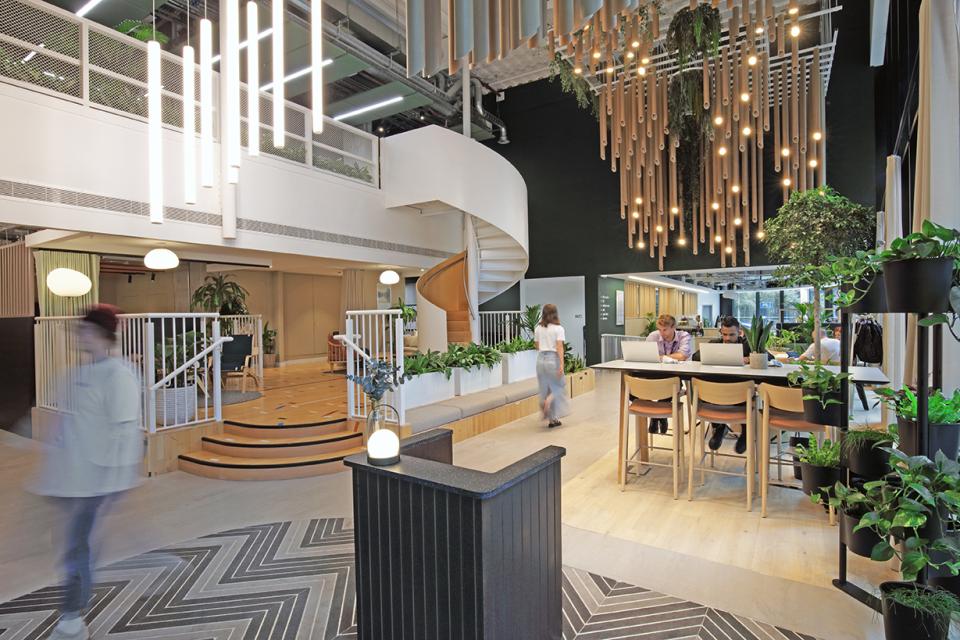 Modern social hub at Eden, New Bailey featuring lighting, greenery, and collaborative spaces promoting community interaction.