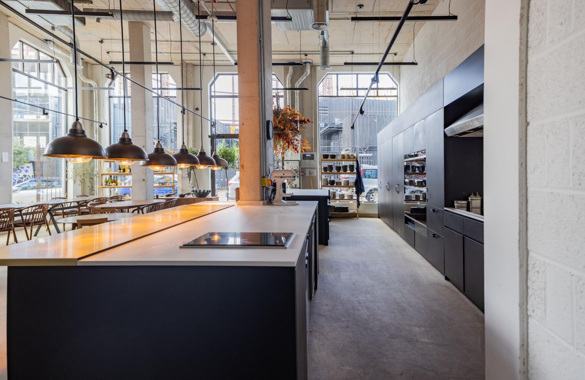 Open kitchen design at The Water House Project showcasing Dekton® surfaces, pendant lighting, and modern dining ambiance.