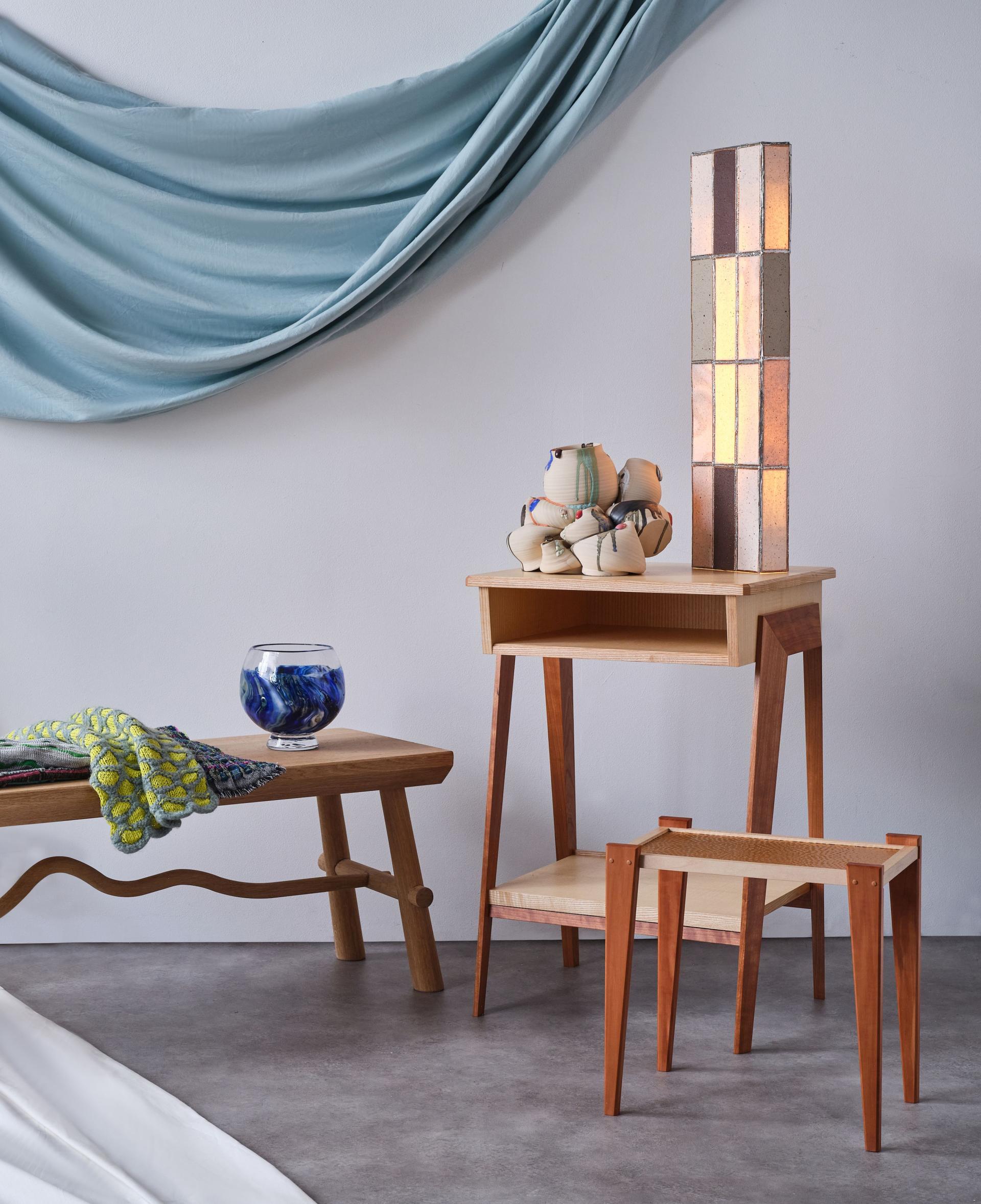 Stylish wooden furniture pieces alongside sustainable decor, showcasing innovative designs at the New Designers event.