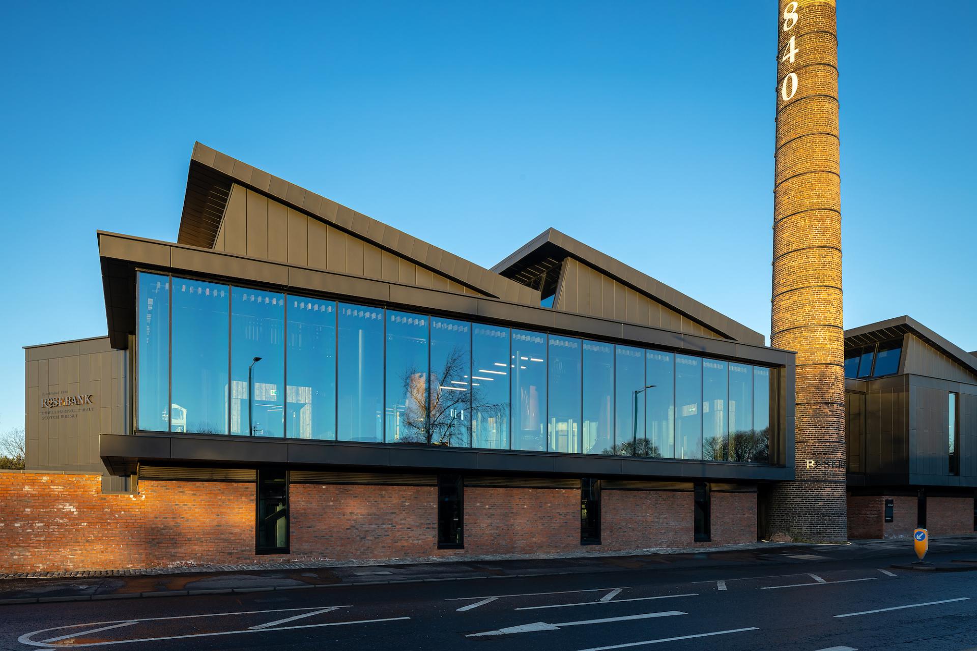 Modern Rosebank Distillery showcases a striking blend of historic architecture and contemporary design with large glass windows.