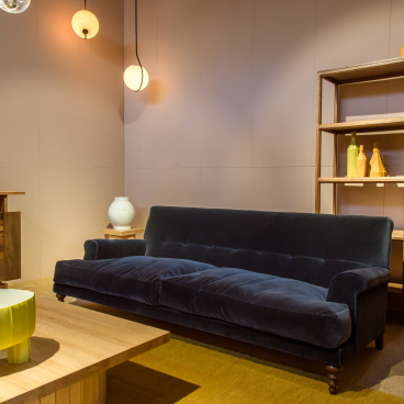 Stylish showroom interior featuring a velvet sofa, wooden furniture, and colorful decor at SCP Pimlico Road in Belgravia.