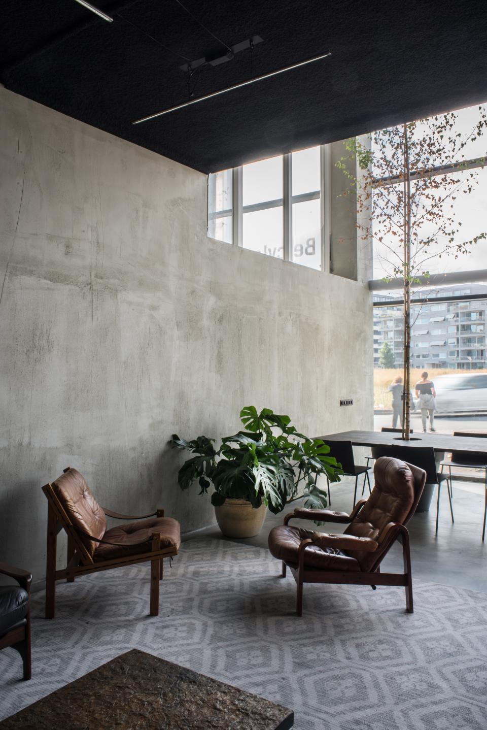 Stylish minimalist interior featuring leather chairs, a plant, and an industrial design at HOP's Public Space in Amsterdam.