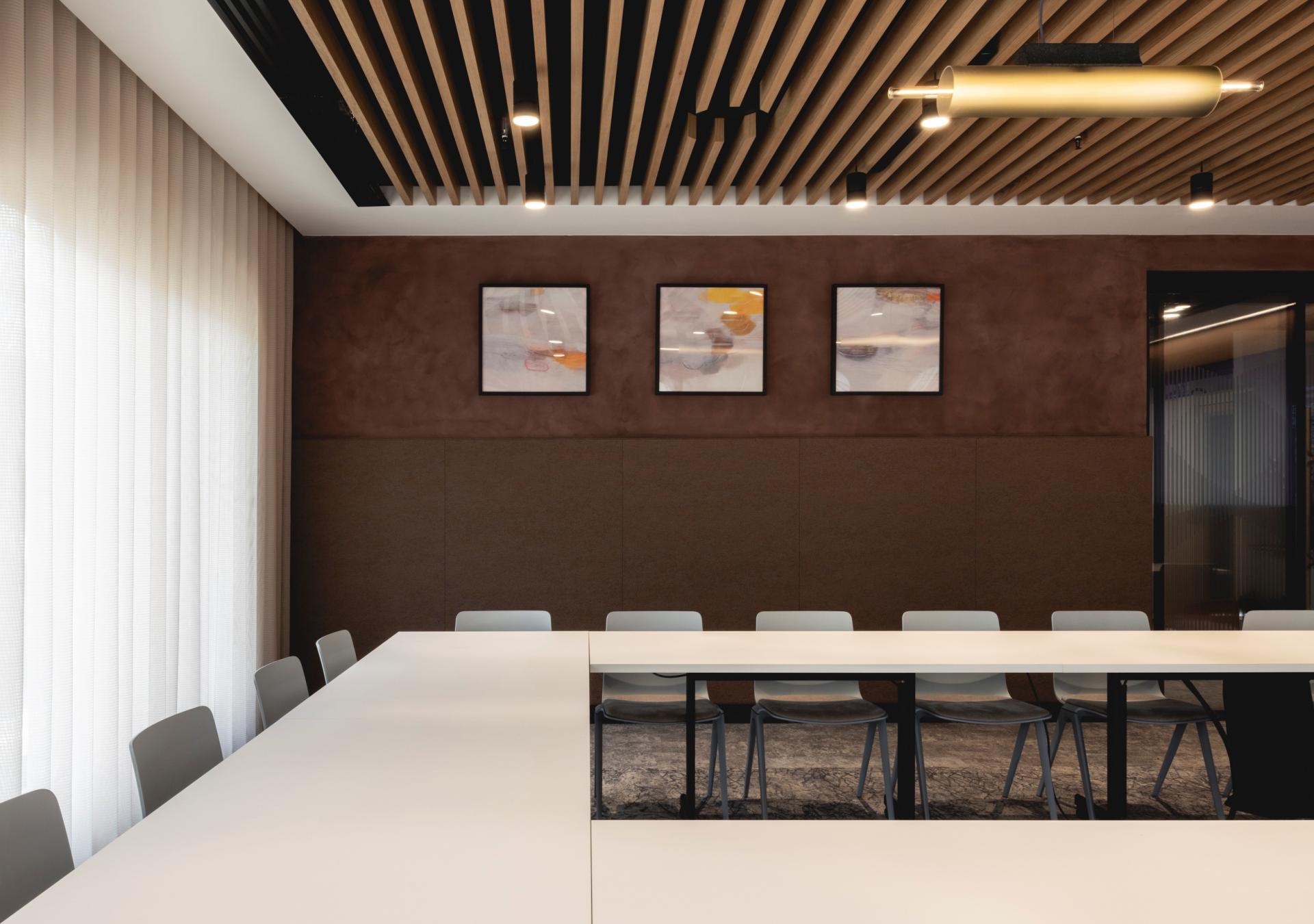 Modern conference room featuring Art Deco-inspired design, wooden ceiling, and artistic wall decor for a tranquil workspace.