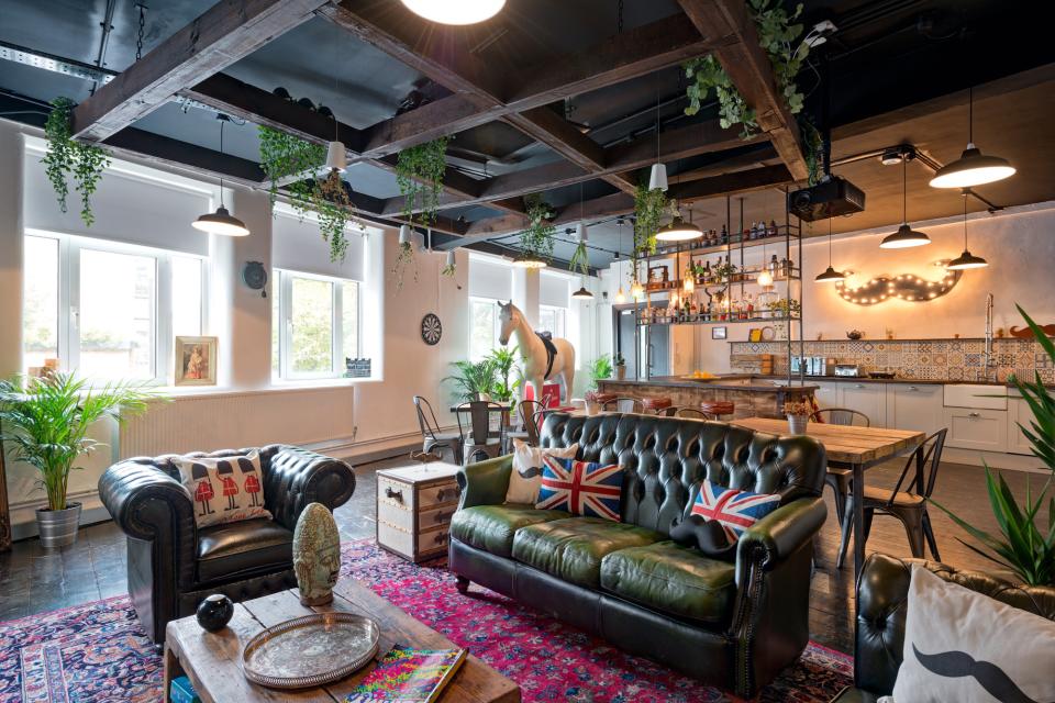 Industrial-inspired office interior of Movember Foundation featuring a green leather sofa, stylish decor, and a unique bar area.