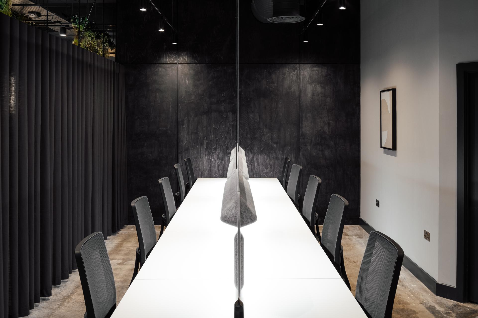 Modern co-working space with a sleek, long white table and ergonomic chairs, designed for collaborative work in Manchester.