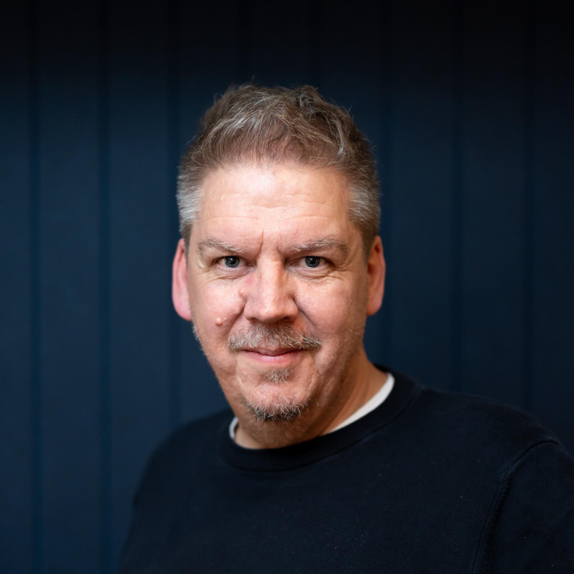 Portrait of a man in a black shirt, symbolizing the changing dynamics of the modern workplace environment.