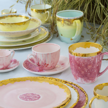 Hand-decorated ceramic and porcelain tableware by Coralla Maiuri, featuring vibrant colors and gold accents.
