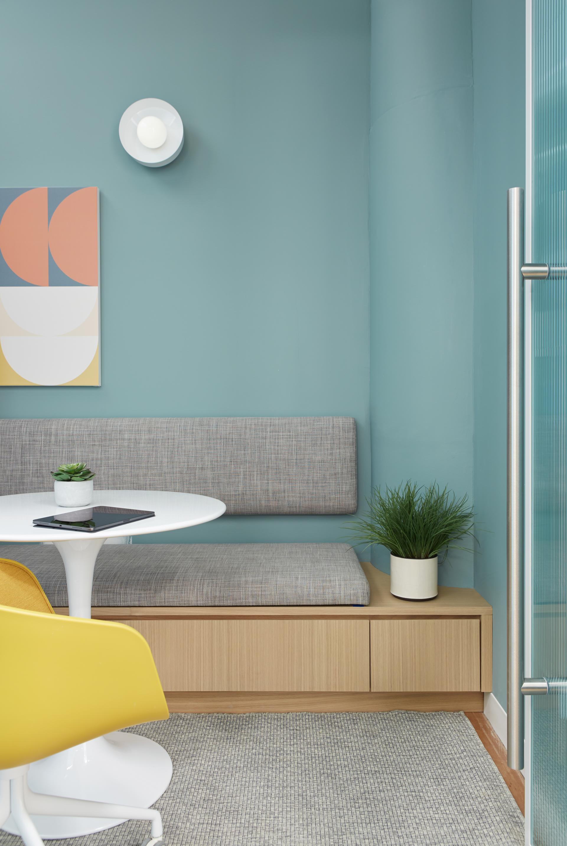 Modern waiting area design featuring nature-inspired elements, a round table, gray seating, and greenery in a medical center.