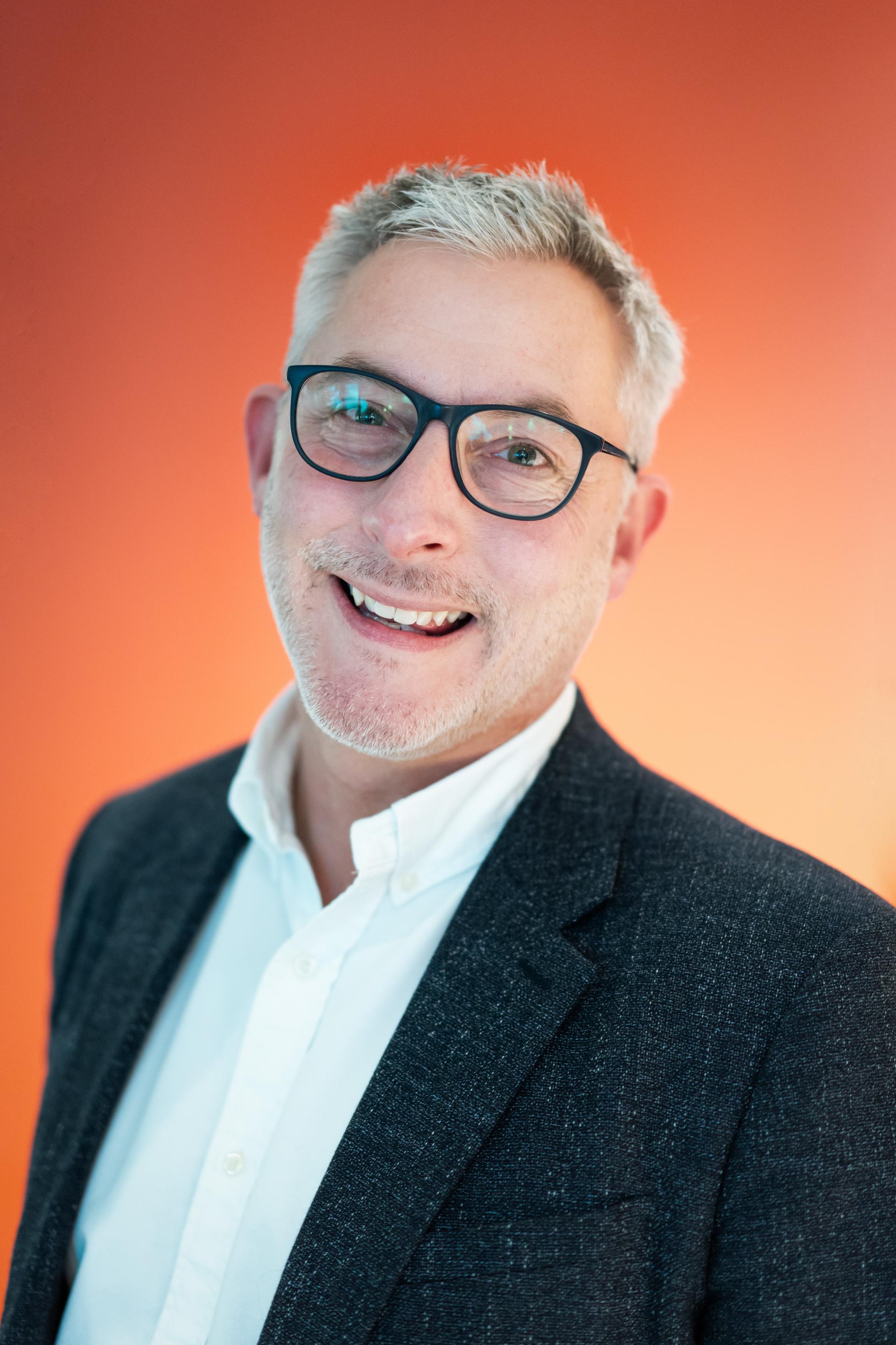 CEO Nick Atkin smiling in a professional setting, highlighting workplace flexibility and leadership in modern business.