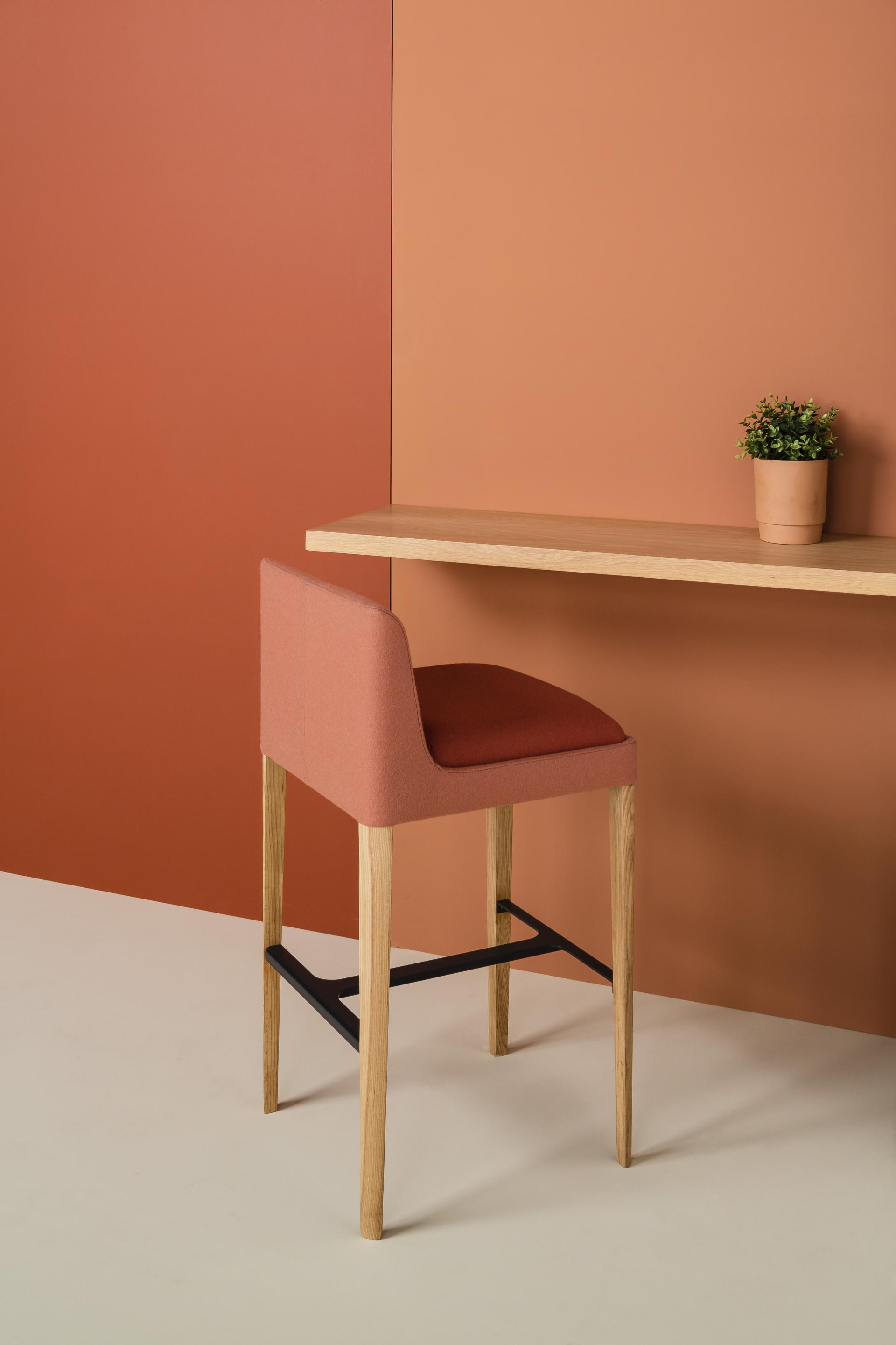 Stylish Kyoto collection bar chair in soft pink fabric with natural wood legs against warm-toned background.