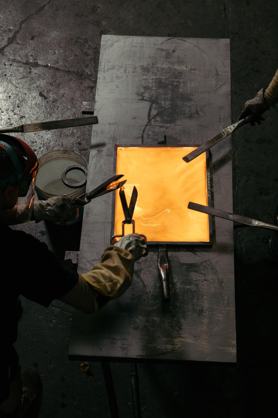 Artisans shaping molten glass on metal workbench, showcasing the craftsmanship behind WonderGlass and nendo’s Melt collection.