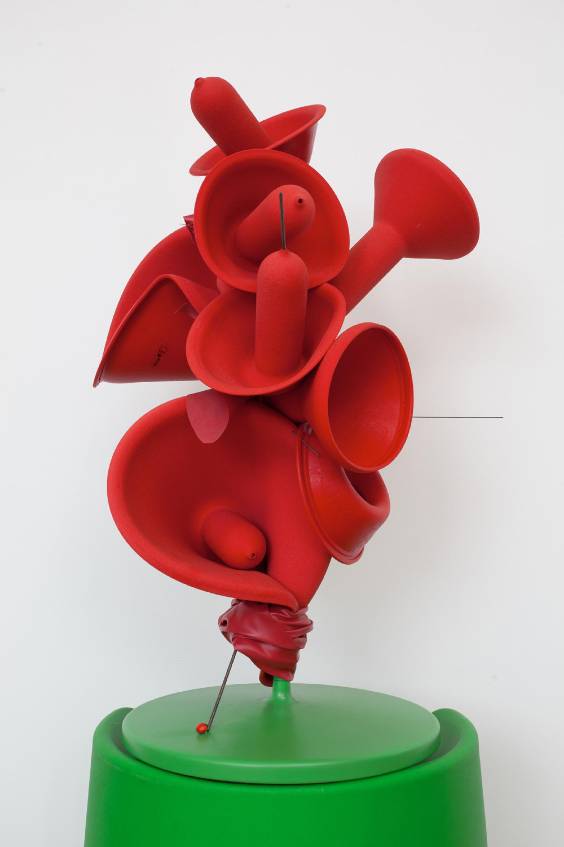 A vibrant red sculpture by Lorenzo Vitturi features abstract forms atop a green base, highlighting innovative design by Established & Sons.