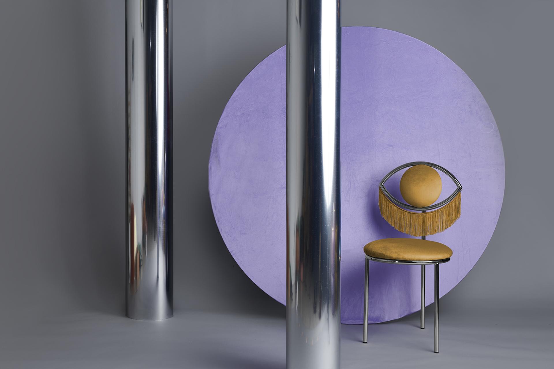 Wink chair designed by Masquespacio, featuring a unique eye motif and vibrant yellow upholstery against a purple backdrop.