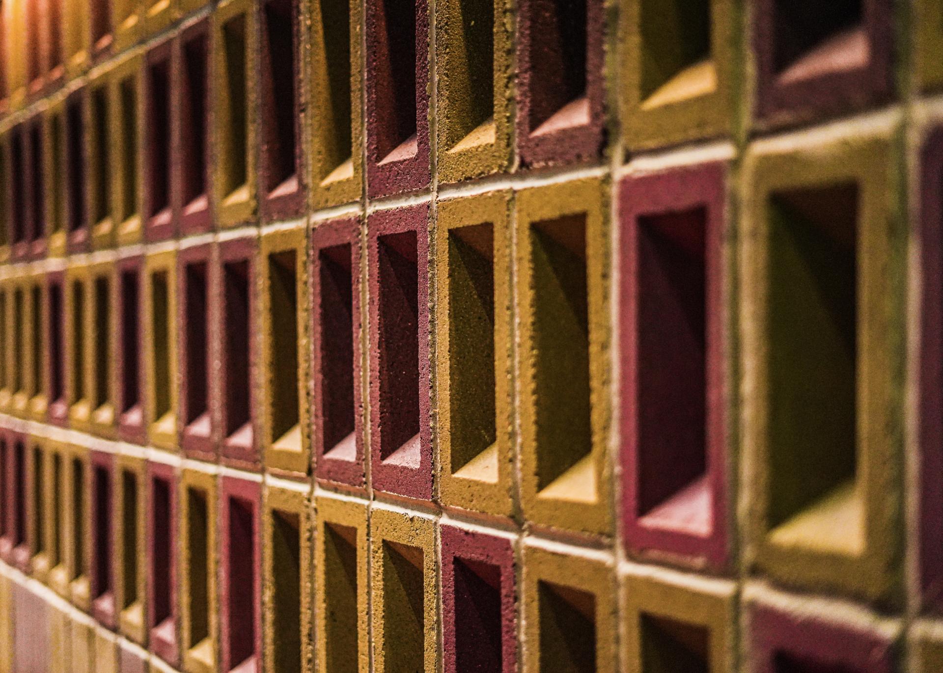 Textured wall of colorful un-fired bricks, showcasing innovative design for sustainable building solutions in the construction industry.